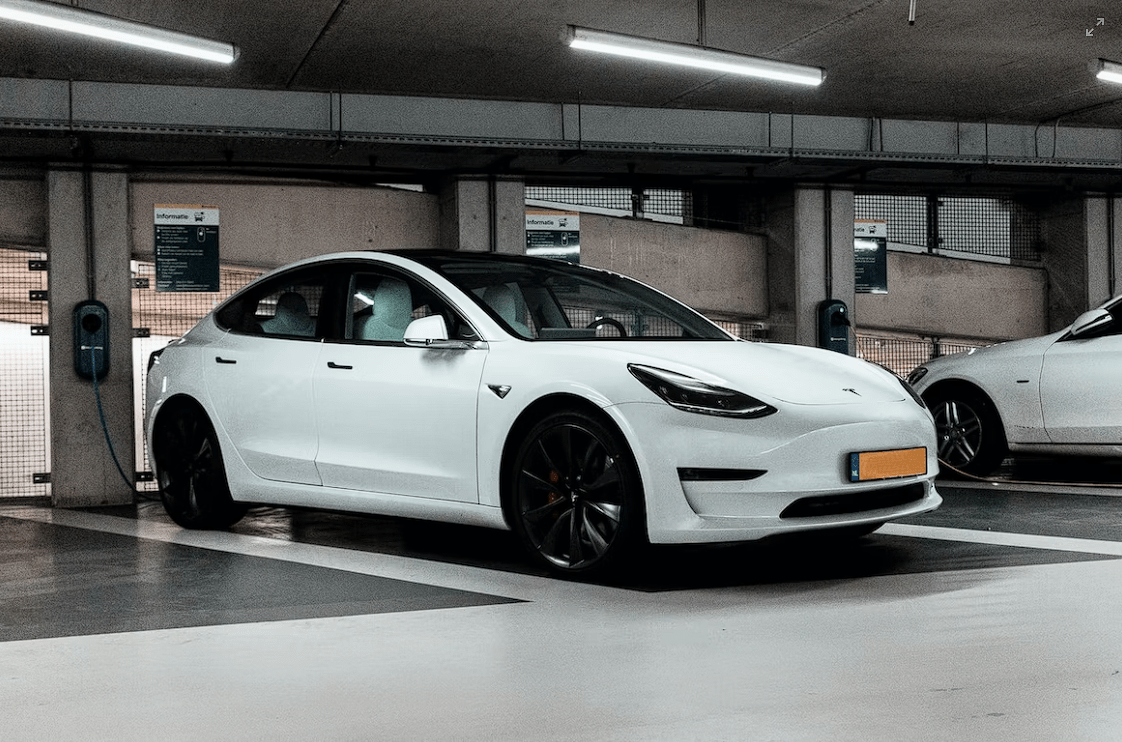 White tesla charging at a parking space