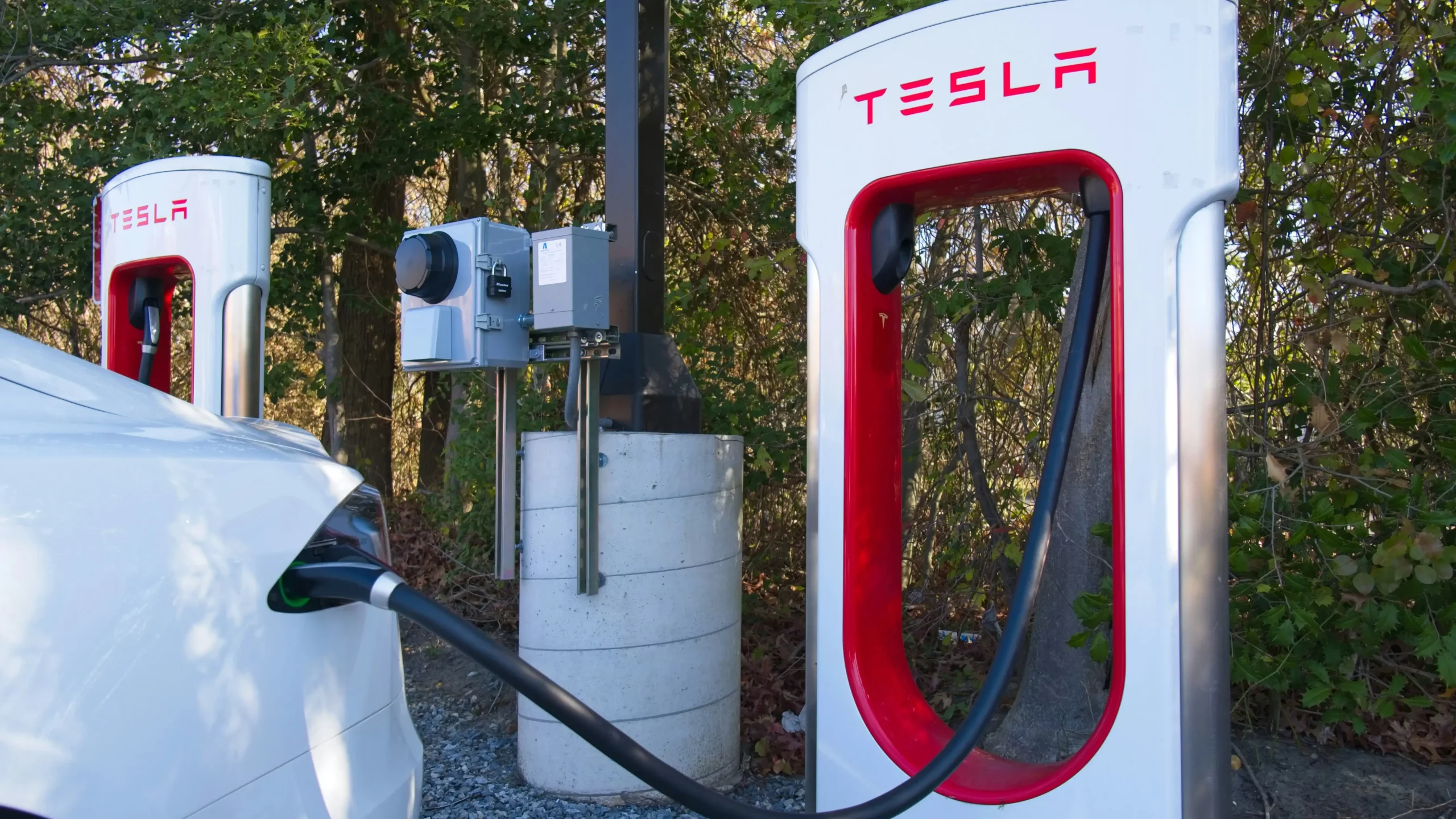 Tesla electric vehicle charging at a station, showcasing the benefits of EV tax credits.