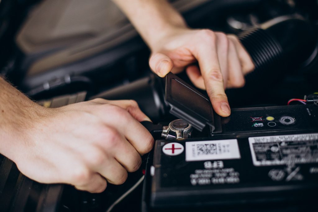 Close-up of a mechanic working on a vehicle’s battery connection, highlighting how post-accident repairs can impact diminished value, influence claim documentation, and affect overall loss assessments.