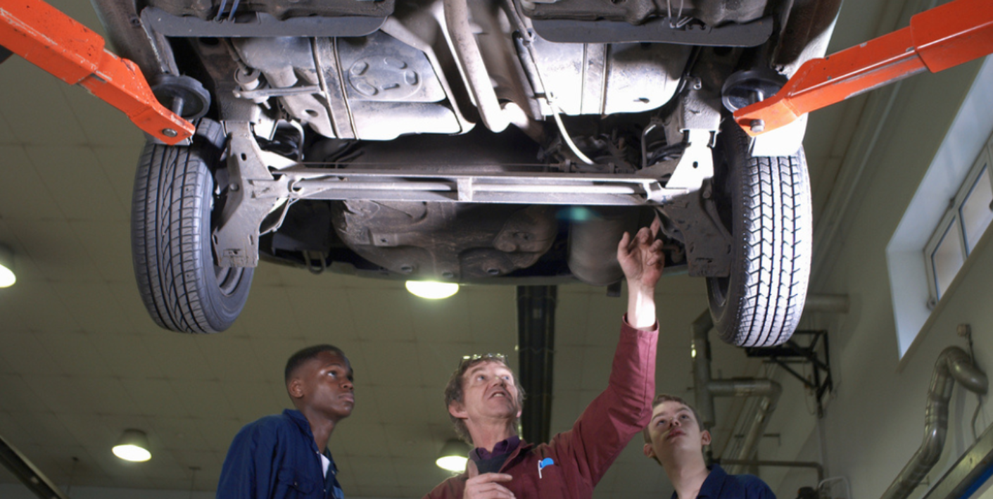 Mechanics inspecting vehicle frame damage on lift illustrating increased diminished value impact in North Carolina