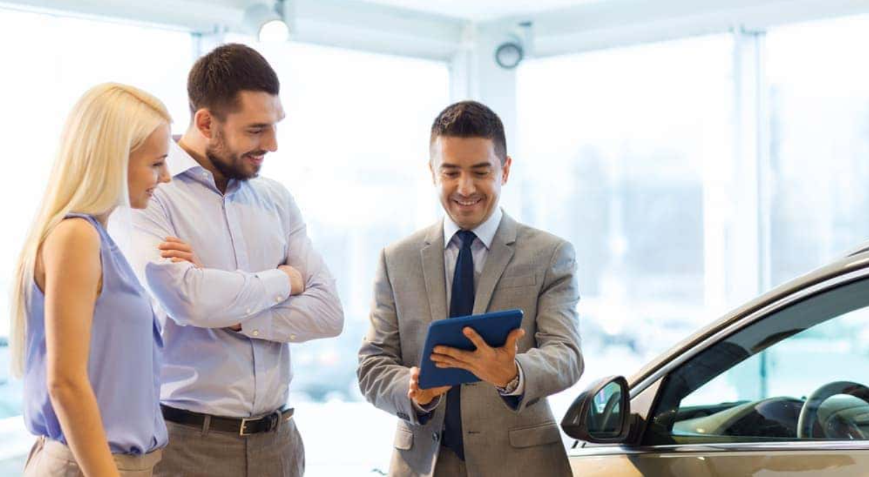 buyers reviewing vehicle history report with dealer while comparing car value after accident