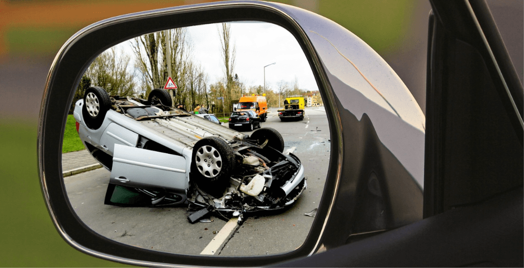 Flipped car after a hit-and-run crash seen through a vehicle side mirror, representing hit-and-run diminished value claims in NC and SC
