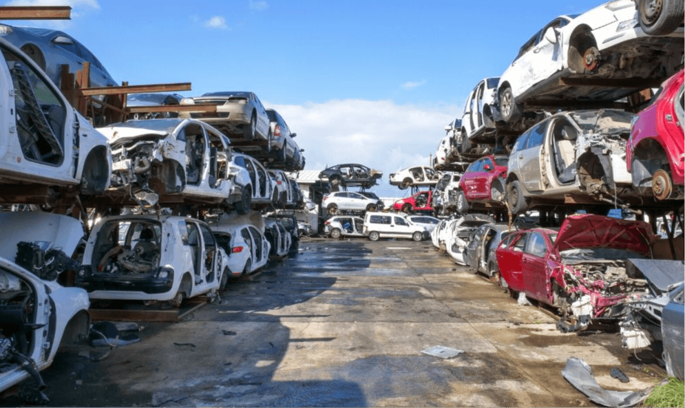 Rows of totaled cars stacked on metal racks in a salvage yard, illustrating record total loss rates affecting Carolina drivers