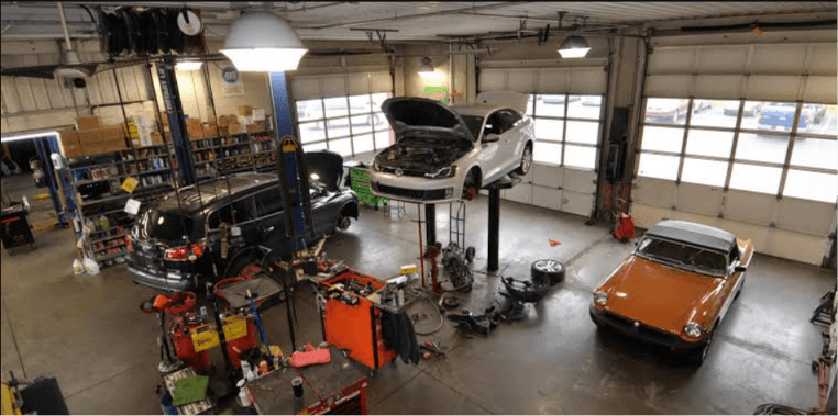 Cars on lifts in a busy collision repair shop, illustrating loss of use during long repair delays in NC and SC